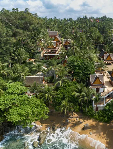 Amanpuri's pavilions nestled amongst dense tropical forest canopy overlooking a flowing river below.