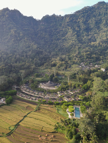 Aerial view of Amanjiwo nestled amongst terraced rice paddies and forested hills in Indonesia.