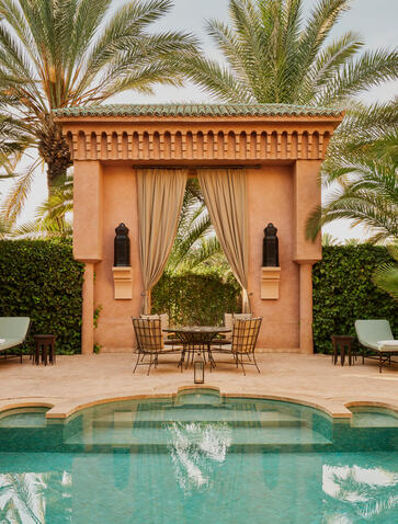Maison avec bassin à Amanjena, vue symétrique avec palmiers et architecture marocaine traditionnelle.