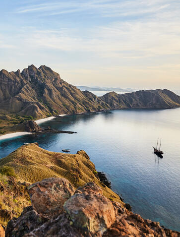 Sailing yacht anchored in turquoise waters beneath volcanic peaks at Amandira.