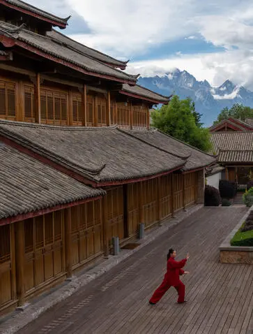 太极练习者在大研安缦度假村的木制平台上，背景为雪山。