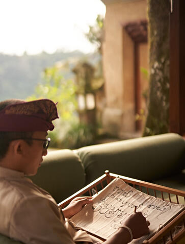 A guest at Amandari learns Aksara Bali script during a cultural class overlooking terraced rice fields.