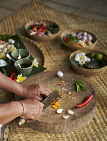 Hands arranging fresh ingredients on a wooden board during a cooking class at Amandari, Bali.