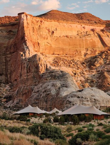Camp Sarika at Amangiri resort, Utah, with canvas tent nestled against rust-coloured canyon walls at sunset.