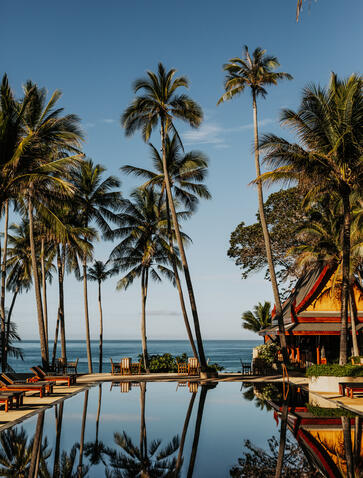 Main pool at Amanpuri surrounded by palm trees and reflecting still water, Thailand.