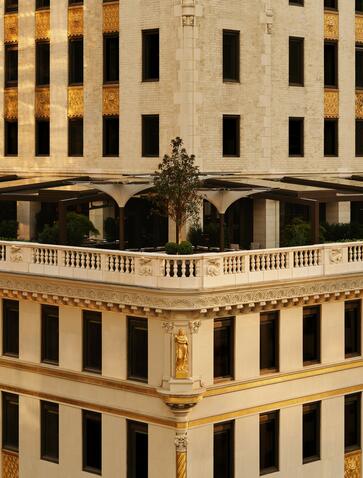 Symmetrical facade of Aman New York's historic Art Deco building with golden stone and arched windows.