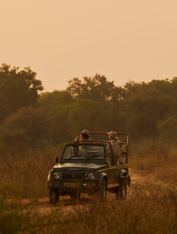 Safari vehicle with open-air seating departing into Indian wilderness at Aman-i-Khas.