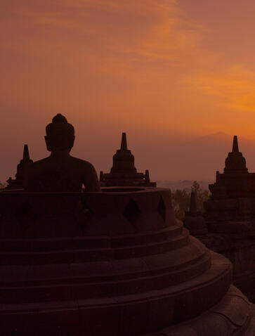 Borobudur temple silhouetted against an orange dawn sky in Indonesia, near Amansara.