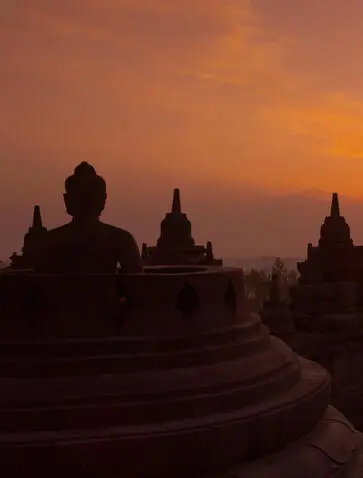 Borobudur temple silhouetted against an orange dawn sky in Indonesia, near Amansara.