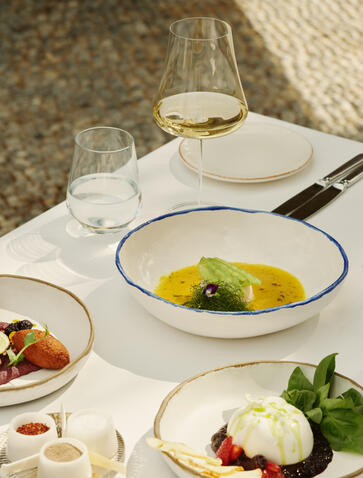 Turkish restaurant dishes at Amanruya, including grilled fish and seasonal vegetables on white plates.