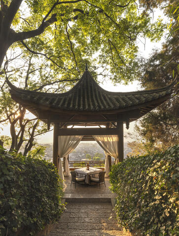 Pavilion with upturned eaves frames the path through verdant gardens at Amandayan, China.