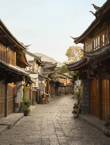 大研安缦度假村的传统石板街道，两侧是木制建筑，晨光柔和。