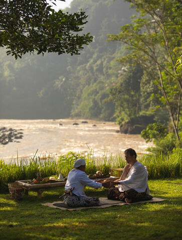 Two guests meditate on the lawn overlooking the river at Amanjiwo resort, Central Java.