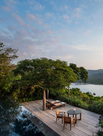 Wooden pavilion with seating overlooking Amanoi's coastal waters and forested landscape at dusk.