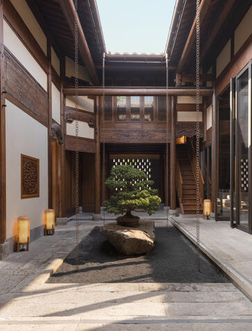 Serene teahouse courtyard at Amanyangyun with traditional timber architecture and sunlit stone pathway.