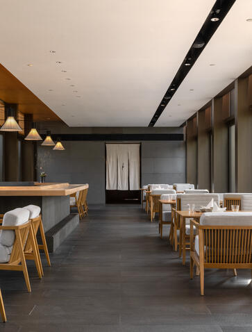 Dining venue at Amanyangyun with wooden chairs, warm lighting, and dark timber interiors.