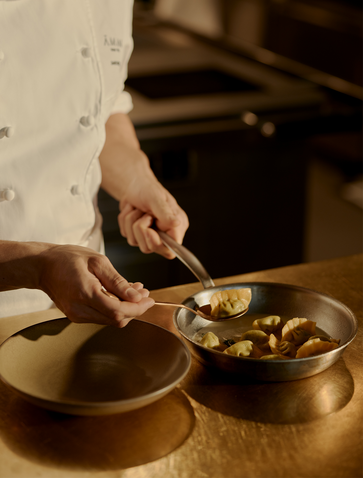 Hand preparing food in brass bowls at Aman New York.