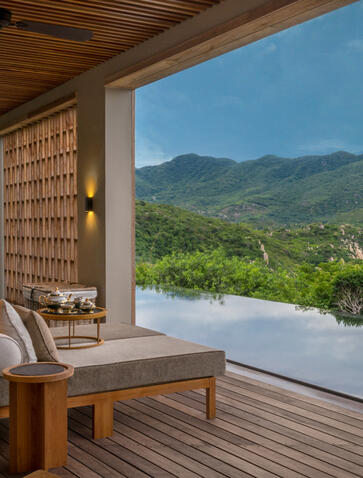 Wellness villa terrace at Amanoi overlooking verdant Vietnamese highlands from a shaded wooden pavilion.