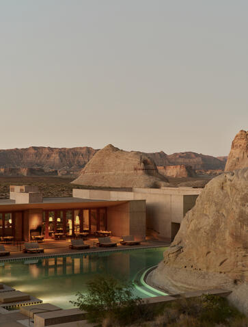 Amangiri's exterior at dusk with illuminated pavilions set against desert rock formations.