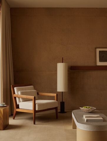 Suite désert à Amangiri, avec fauteuil bois clair et mobilier minimaliste dans des tons terreux.