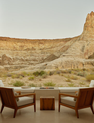 Deux fauteuils en cuir face à une baie vitrée offrant une vue sur les formations rocheuses désertiques d'Amangiri, resort.