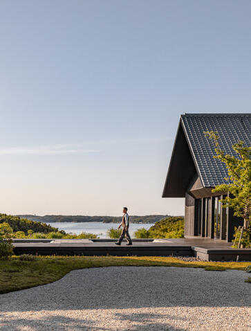 Amanemu resort exterior with modern timber building overlooking Japanese coastal landscape at dusk.
