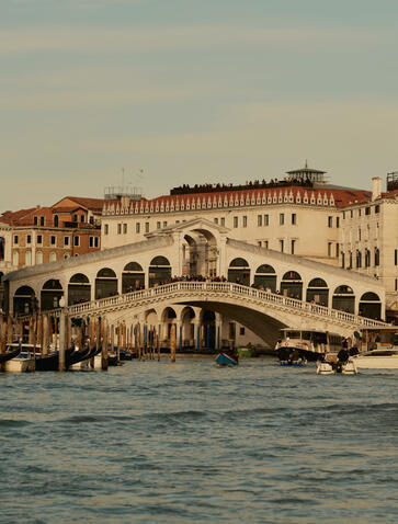 Exterior view of Aman Venice overlooking the Grand Canal and Rialto Bridge at dusk.