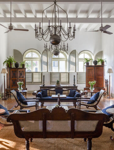 Amangalla's colonial-style lounge with high ceilings, chandelier, dark wooden furniture and arched windows.