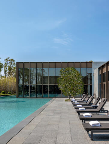 Amanyangyun swimming pool with turquoise water, lounge chairs, and modern pavilion under clear sky.