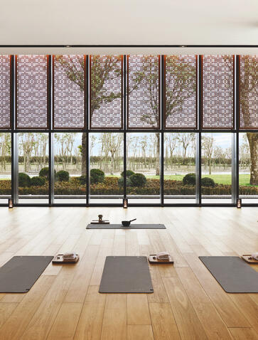 Amanyangyun pilates studio with wooden floor, yoga mats, and floor-to-ceiling windows overlooking gardens.