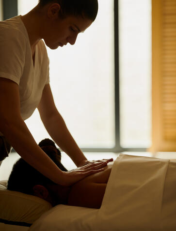 Therapist applying treatment to guest's back at Amanzoe resort spa, Greece.