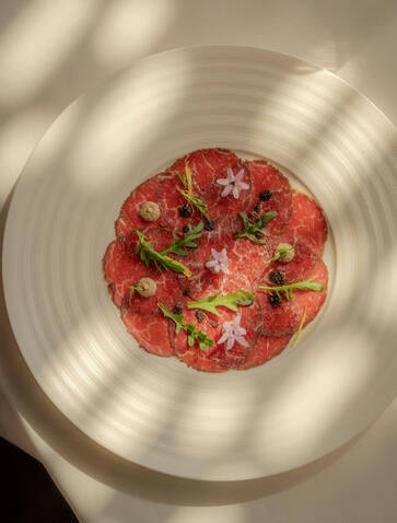 Plate of fresh raspberries and pistachios at Amanyangyun, dappled with sunlight.