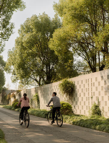 Guests cycling along a tree-lined path at Amanyangyun, China.