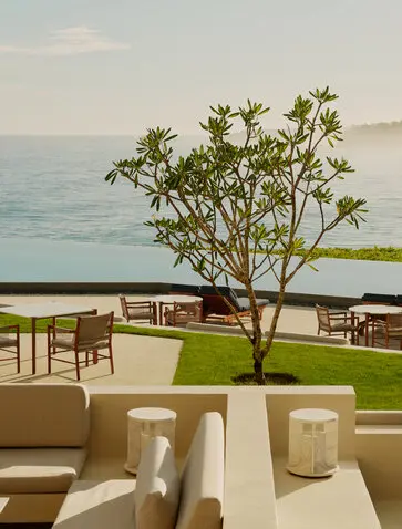 Amanera's beachfront bar terrace with dining tables, a solitary tree, and Caribbean Sea views.
