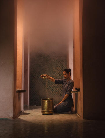 Silhouette d'une personne assise dans une alcôve éclairée à la lueur dorée à Amanjena resort.