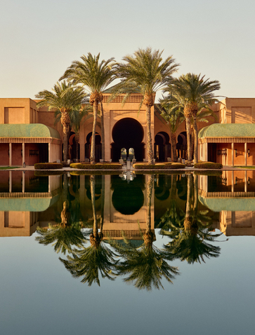 Amanjena resort's central basin reflecting the main pavilion and palm trees at sunrise, Marrakech.