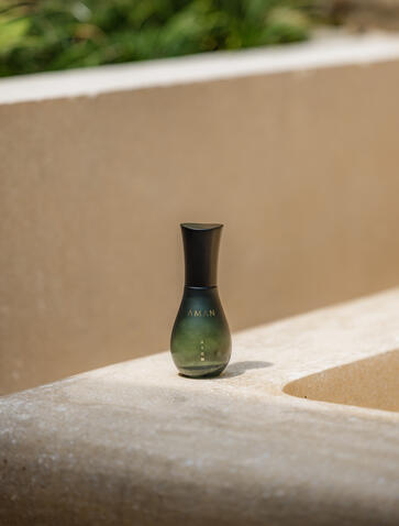 安缦齐和度假村中，一只绿色玻璃瓶放在混凝土台面上。