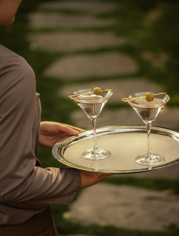 Staff member carrying a tray with two martini cocktails at Amanyangyun, China.
