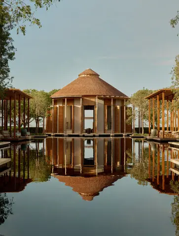 Amanyara's distinctive circular wooden pavilion reflected in still water, surrounded by mangrove trees.