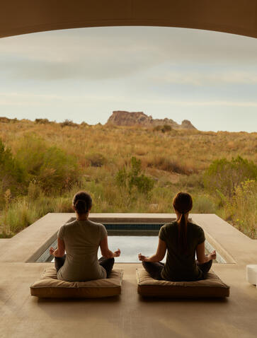 Due meditanti seduti nel padiglione spa di Amangiri, con vista sul paesaggio desertico.