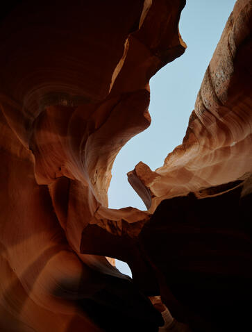Sunlight filters through towering red rock walls of a slot canyon at Amangiri.