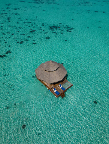 Floating Kawayan Bar at Amanpulo, a thatched-roof structure anchored in turquoise waters.