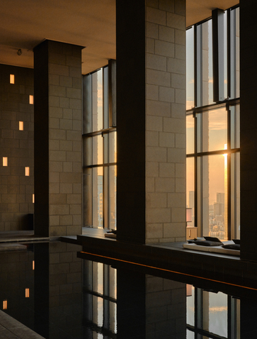 Spa wellness area at Aman Tokyo with tall windows casting geometric light across dark stone surfaces.