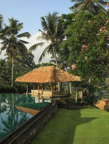 Resort swimming pool at Amandari with thatched pavilion and manicured gardens, Indonesia.