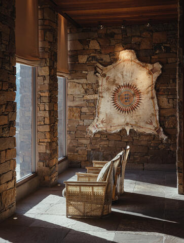 Entrance lobby at Amangani with stone walls, wooden beams, and a large mounted elk skull above a rustic wooden bench.