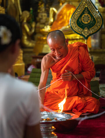 Buddhist monk in red robes conducting a blessing ceremony at Amantaka.