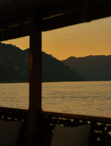 Wooden post framing a golden sunset over calm water at Amantaka wellness spa.