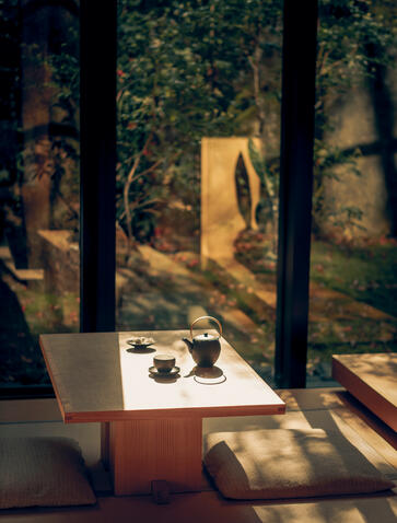 Afternoon tea service at a table with garden views through tall windows at Aman Kyoto.