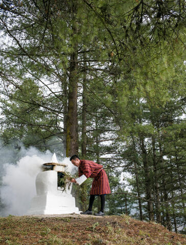 Buddhist fumigation ceremony at Gangtey Lodge, Aman Bhutan, with monks in traditional robes performing ritual amongst forest trees.