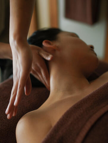 Therapist's hands performing a shoulder massage during a spa wellness treatment at Aman.